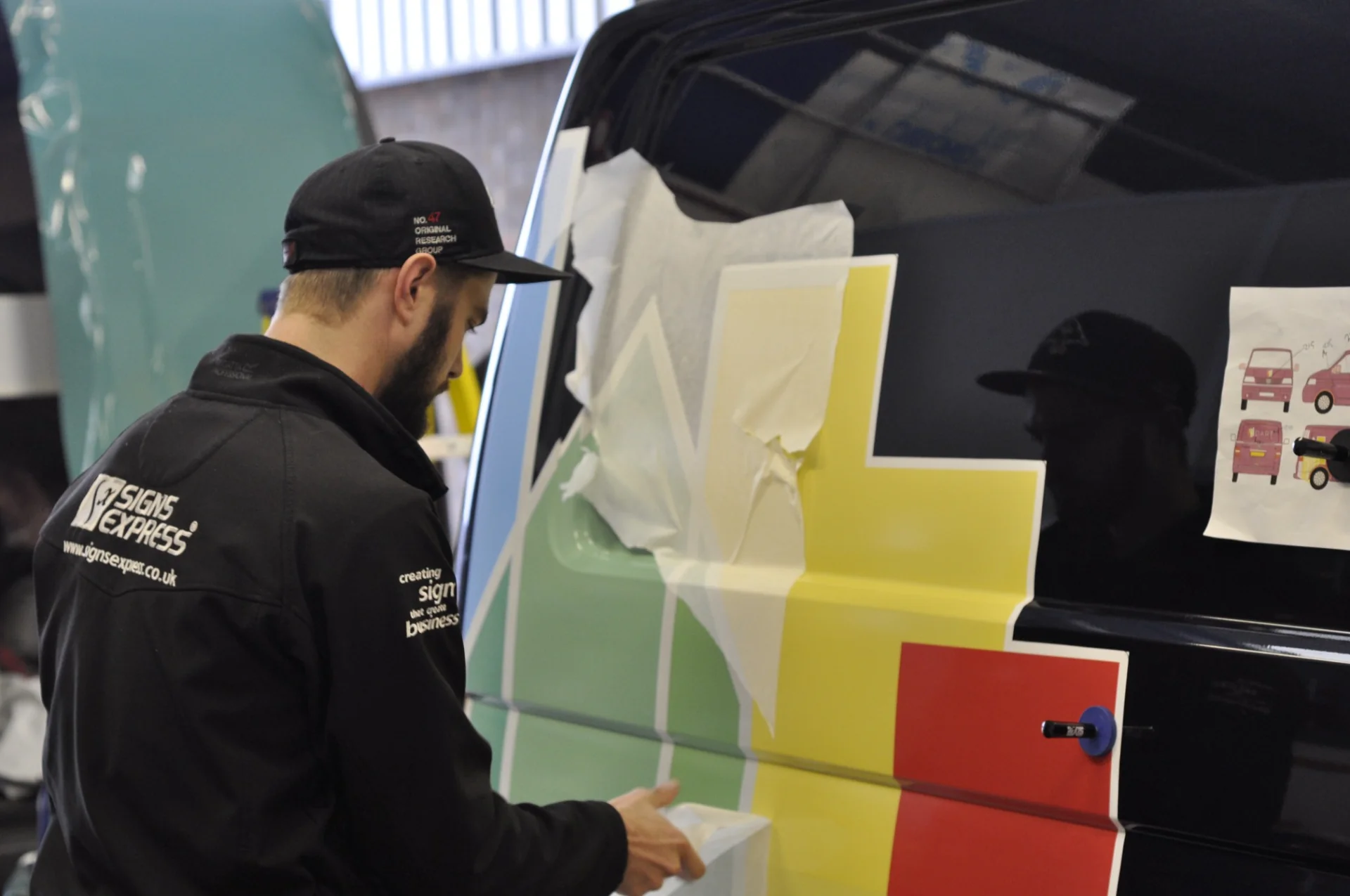 Sign fitter applying DART’s colourful brand graphics to the side of a van