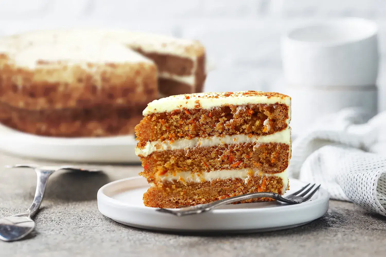 Slice of Rhokett carrot cake with layered icing on a plate